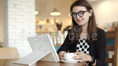 女人<strong>坐在餐馆</strong>的桌子旁。 带着可以上网的平板电脑